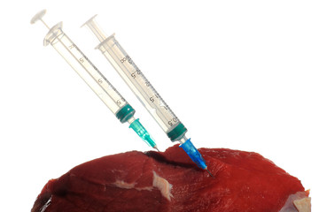 Syringe in a pork meat. White isolated background.