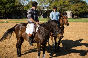 Two male friends riding horse in the ranch