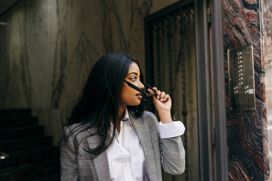 Stylish woman putting on sunglasses