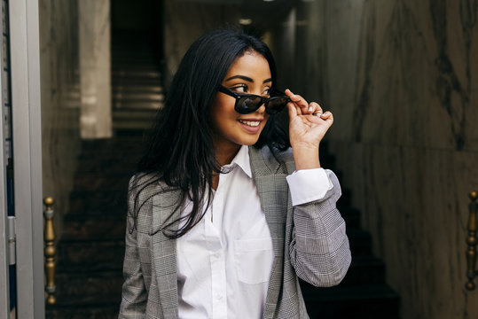 Stylish woman putting on sunglasses