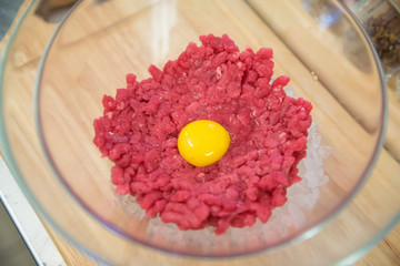Transparent bull with meat for tartare and a egg yolk. Top view