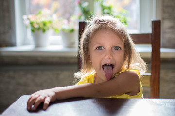 child in the room on the window background is crooked, having fun, playing, showing tongue © Anatoly Tiplyashin