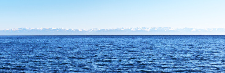 Fototapeta premium Panoramic view of Lake Baikal and snow-covered mountains on the opposite east coast. Water background