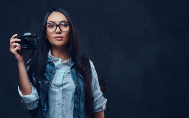 A woman with backpack holds compact photo camera.