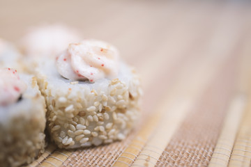 Sushi rolls with sesame and sauce close-up in defocus