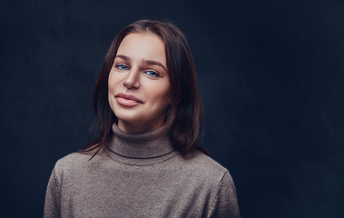 A woman dressed in a long neck brown jacket.