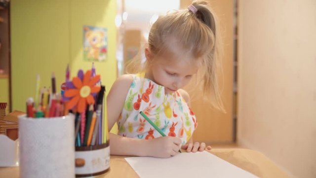 Little girl writing and drawing. Doing homeworks. Child. Adorable girl.