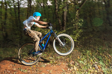 Fototapeta na wymiar a young guy in a helmet flies landed on a bicycle after jumping from a kicker