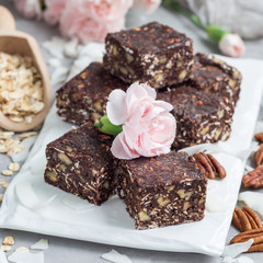 Paleo chocolate energy bars with rolled oats, pecan nuts, dates, chia seeds and coconut flakes, square