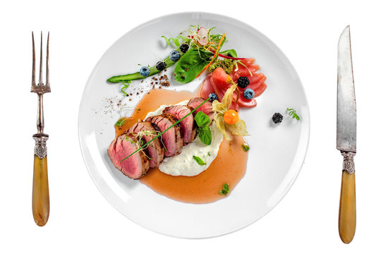 Gourmet medium rare meat steak with sauce and fresh salad. Healthy meal made of meat fillet and fresh vegetables isolated on white background. Top view.