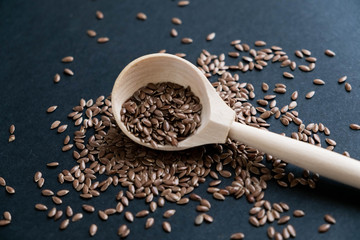 Flax seeds in spoons over dark background. Natural light. Selective focus. Close up on a black background. Top view, flat lay. copy space