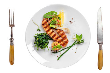 Plate with delicious grilled salmon fish steak and salad isolated on white background. Healthy food made of fish and vegetables. Top view.