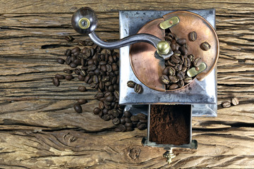 vintage coffee grinder with manufacture roasted Indonesian Arabica coffee beans on rustic wooden background