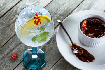 Alcoholic gin and tonic cocktail with sweet chocolate mousse on a wooden table.