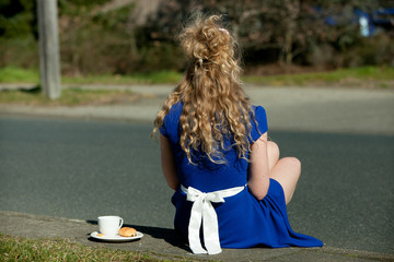 pretty blonde girl in fancy blue dress  enjoys a coffee on the street