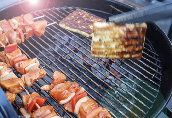 The cook prepares a delicious meat shish kebab with vegetables on the grill and turns the cheese on the grill in motion.