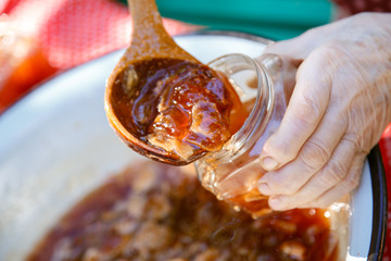 Hands pour jam from apples into jars. The process of preparing jam. Jam from apples.