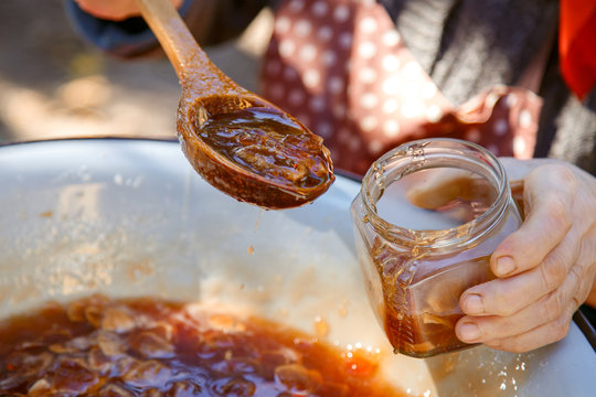 Hands pour jam from apples into jars. The process of preparing jam. Jam from apples.