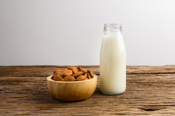 Peeled almonds with bowl and Bottle of almond milk on rustic wooden
