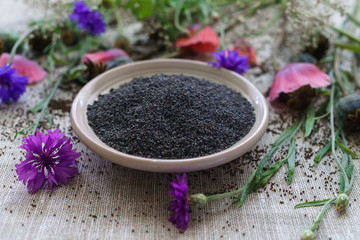 Ripe poppy heads, along with seeds and poppy flowers on the table.