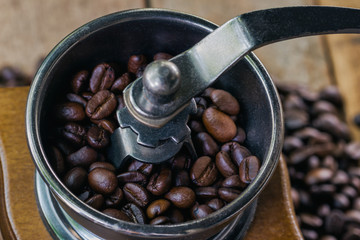 Close up coffee beans on grinding by rotary coffee grinder. Good morning with homemade fresh coffee. Antique coffee grinders for grinding coffee beans for breakfast. Macro concept in vintage style.