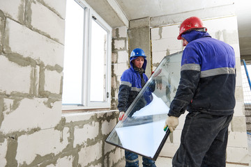 windows installation. Two construction workers installing glass