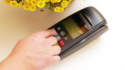 Payment by Gold Card with terminal machine and entering the pin code On white table with yellow flowers, 4k video - Powered by Adobe