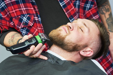 Beard care. man while trimming his facial hair cut at the barbershop