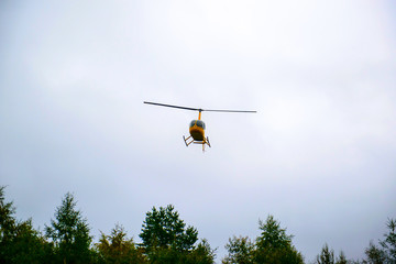 Fototapeta na wymiar A yellow helicopter flying in the sky. Air transport in the sky. Useful aircraft helicopters. Aircraft emergency help.