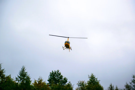 A yellow helicopter flying in the sky. Air transport in the sky. Useful aircraft helicopters. Aircraft emergency help.