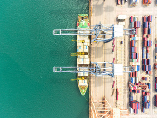 Aerial view of large shipping port with goods cargo containers, cranes and shipping vessels.