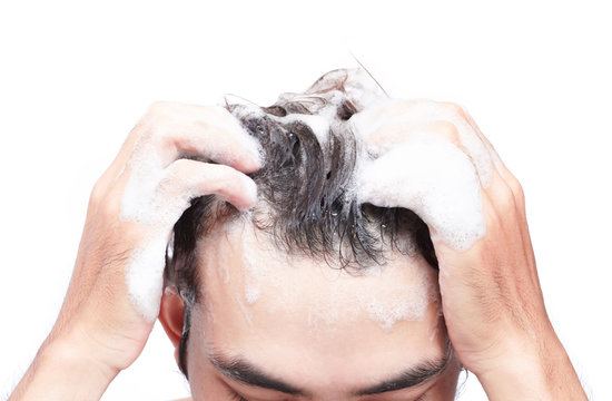 Closeup young man washing hair with white background, health care concept