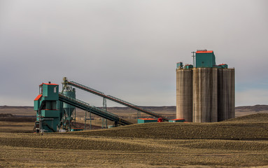 Tall cement silos and conveyors in a coal mining pit in a Wyoming countryside landscape
