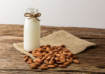 Peeled almonds with bowl and Bottle of almond milk on rustic wooden