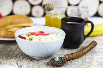 healthy breakfast - oatmeal with fruit in a bowl next to rustic spoon