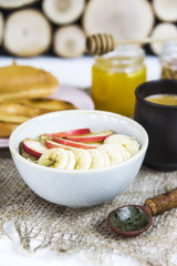 healthy breakfast - oatmeal with fruit in a bowl next to rustic spoon