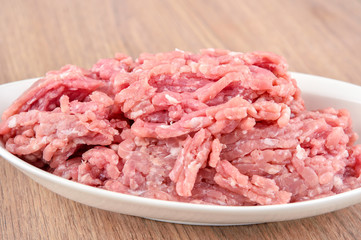 ground pork in a white plate on wooden table