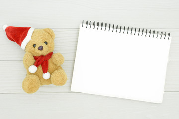 Christmas bear and white book with top view and copy space on the white wooden table. Christmas holiday concept.