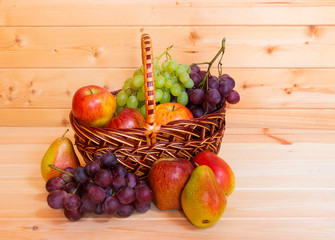 Fresh fruits in basket on wooden background