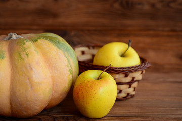 Sweet pumpkin and apples on a wooden background. Autumn harvest. Healthy diet. Closeup