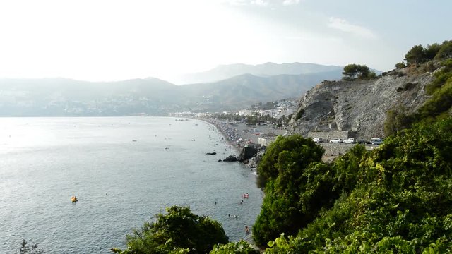 Landscape of mediterranean beach with mountains and people bathing in summer