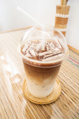 Ice latte in plastic cup. Pastel color tone. Favorite beverage for coffee and milk lover. Cafe view.