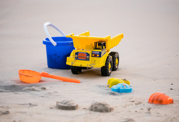 Obraz premium Beach toys series. The yellow truck, blue tank and scoop device. On the beach in holiday concept.