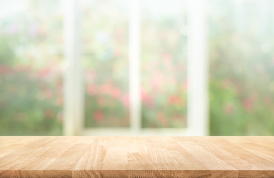 Wood table top on blur of window with garden flower background in morning.For montage product display or key visual layout.