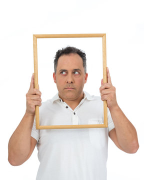 Funny man uses a frame to frame himself. He is overweight and is wearing a white polo..