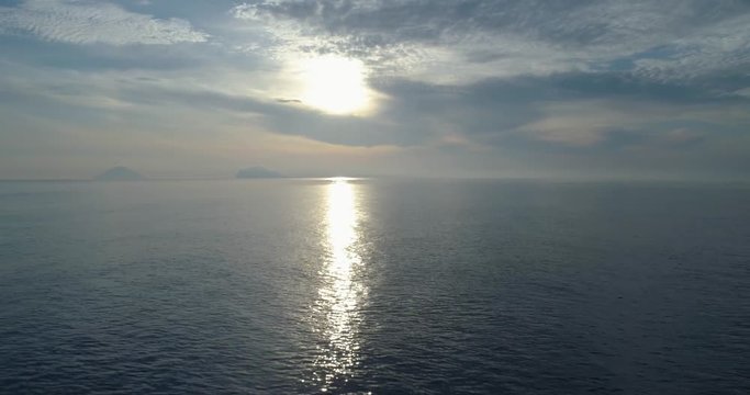 moving backward aerial view of mediterranean sea shore beach in Salina with far Stromboli volcano.Nature outdoors travel establisher,Italy,Sicily Eolian Island.Summer.4k drone establishing video