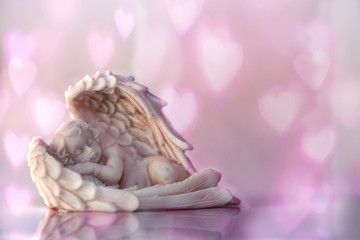 Postcard to St. Valentine's Day: an angel figure with a bokeh heart background