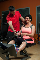 Fototapeta na wymiar Brunette woman exercising in gym with coach