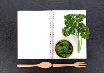 Notebook and parsley isolated on black background