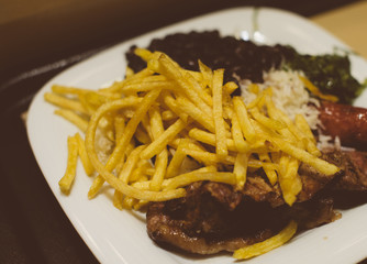 Junk food concept. French fries with rice and fried meat.